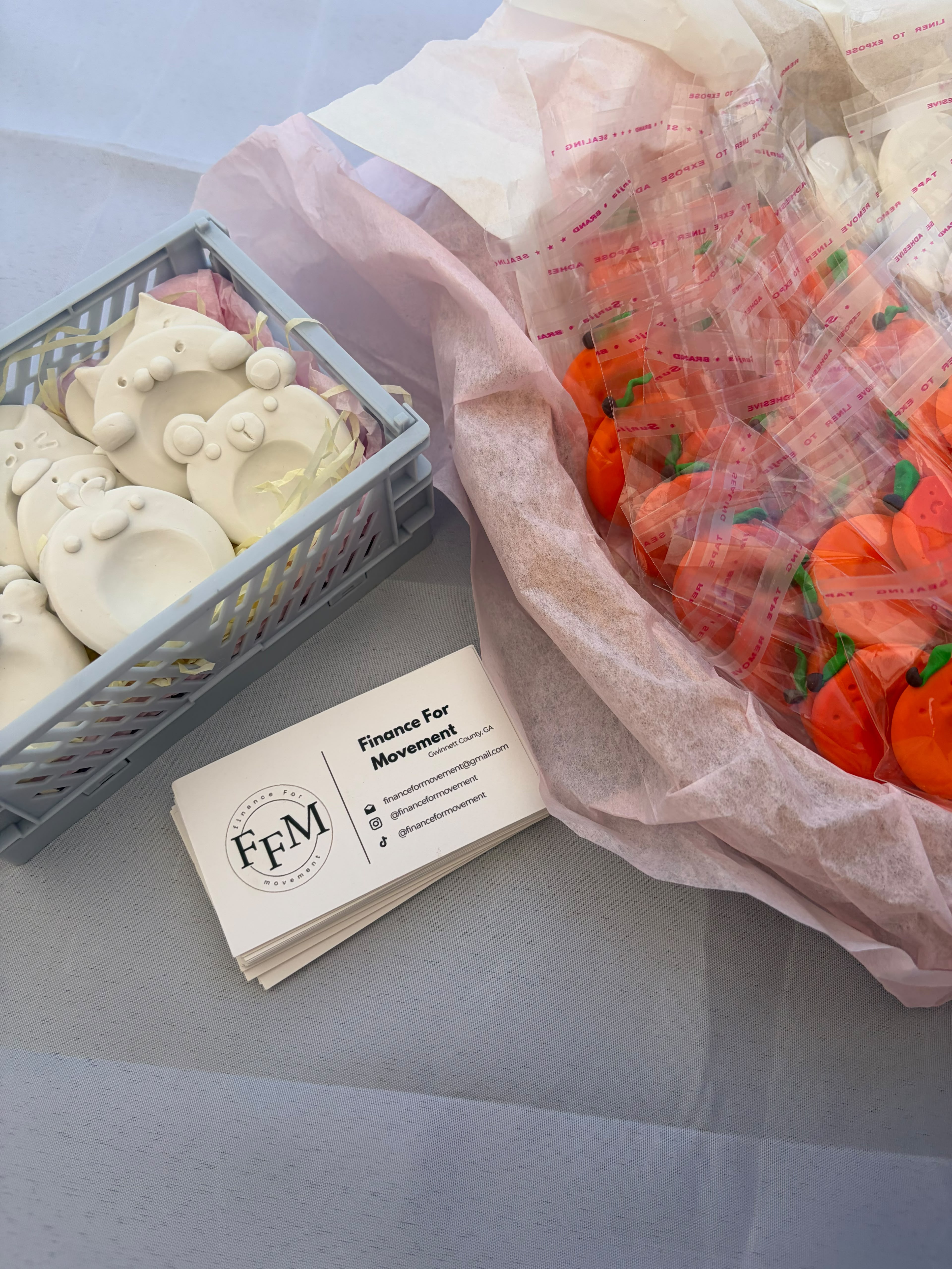 Handmade clay figurines beside Finance For Movement business cards.